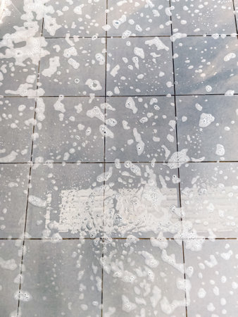Bubbles from cleaning on tile floor. Wet floor during washing and cleaning. Danger of slipping and falling on slippery surface. Concept of accident and injury. Soap suds or foam and bubblesの写真素材