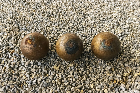 Old three rusty Petanque on placed in pebble. Used petanque balls on a stone ground. The iron ball is rusty around the surface. Rusty Petanque ball on the ground with surround by the rock or pebble.の写真素材