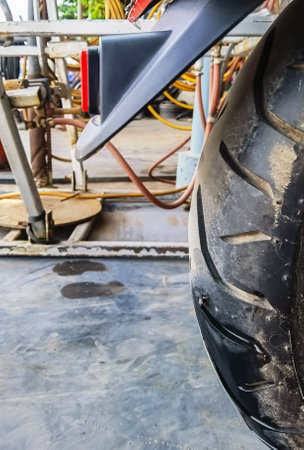 Motorcycle tire punctured by nail. Damaged motorcycle tire had air leaking from rubber. Screw nail or Iron stuck puncturing motorcycle or big scooter tire at garage. Motorcycle repair and maintenance.の写真素材
