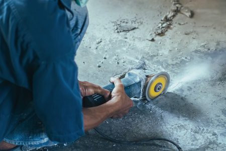 Worker of water utility maintenance service using angle grinder to change sewer manholes in house. Old man change and repair sewer cover of sewerage system. Maintenance of toilet drainage systemの写真素材