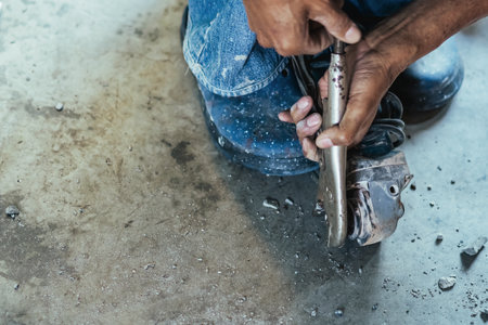 Worker of water utility maintenance service using angle grinder to change sewer manholes in house. Old man change and repair brass sewer cover of sewerage system. Maintenance of toilet drainage systemの写真素材
