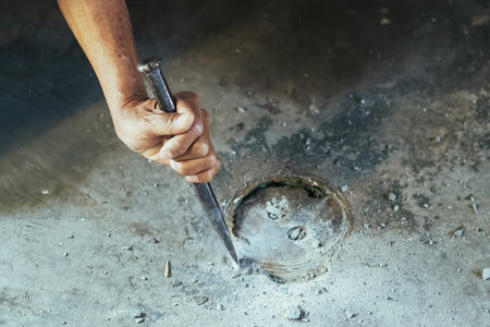 Elderly worker of water utility maintenance service changing sewer manholes in house. Hands of old...