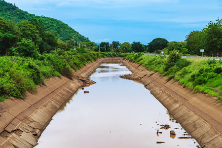 Irrigation canal or irrigation channel in cracked concrete wall send water from reservoir to agricultural area. Old broken Irrigation ditch in plain of River.の写真素材