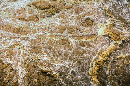 Smudged water flows profusely. River water flowing profusely. Flood waters rushing down river after storm flows through. Turbulent river dam. Water turbulence of river due to dam. Water Nature Textureの写真素材