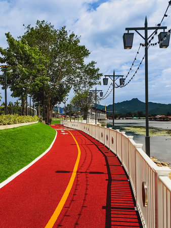 View of beautiful public walking path or running track made of artificial grass turf along riverside for people to exercise, enjoy beautiful scenery and breathe fresh air in Kanchanaburi, Thailand.の写真素材