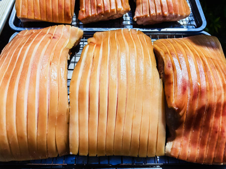 Pork belly with scored skin resting on tray to dry in sun, showing gelatinous layers and golden tones. Ideal for cooking process or food prepare concept. Process of making delicious crispy pork.の写真素材