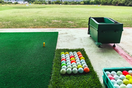 A tee for driving golf on artificial green grass or green turf at practice range with golf driving range background. Playing and practicing with golf swing at golf driving range. Selective focus.の写真素材