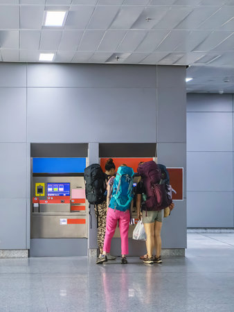 Group of caucasian women passengers with backpack buy transport ticket from ticket vending machine. Female tourist buy ticket from automatic vending machine together. Travel and Adventure concept.の写真素材