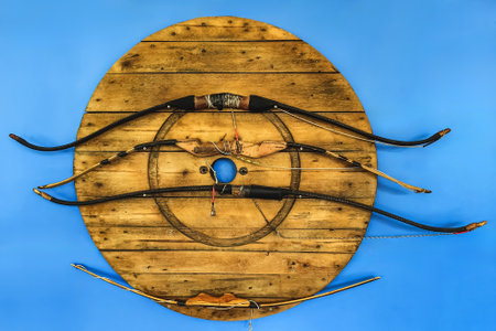Collection of old classic handicraft wooden bows handle hang on wall as decorations. Wooden bow handles display on wall. Old classic traditional bow for archery training. Traditional hunting and sportの写真素材