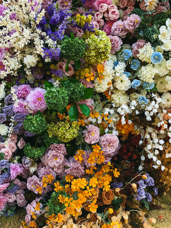 Decorated and embellished with beautiful vibrant artificial flower bouquets arrangements. Colorful artificial flowers as background or backdrop. Multicolored floral pattern wallpaper. Adorned flowersの写真素材