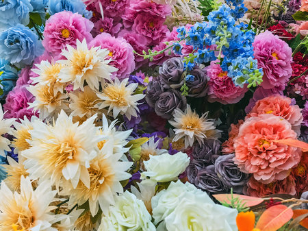 Decorated and embellished with beautiful vibrant artificial flower bouquets arrangements. Colorful artificial flowers as background or backdrop. Multicolored floral pattern wallpaper. Adorned flowersの写真素材