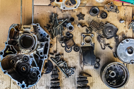 Old parts of motorcycles background. Repair and maintenance old parts of engine. Old motorcycle spare parts on corrugated paper background. Disassembly of spare parts, gear, differential, engine, old.の写真素材