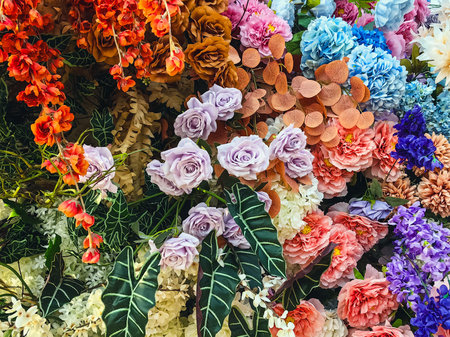 Decorated and embellished with beautiful vibrant artificial flower bouquets arrangements. Colorful artificial flowers as background or backdrop. Multicolored floral pattern wallpaper. Adorned flowersの写真素材