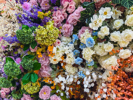 Decorated and embellished with beautiful vibrant artificial flower bouquets arrangements. Colorful artificial flowers as background or backdrop. Multicolored floral pattern wallpaper. Adorned flowersの写真素材