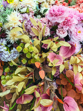 Decorated and embellished with beautiful vibrant artificial flower bouquets arrangements. Colorful artificial flowers as background or backdrop. Multicolored floral pattern wallpaper. Adorned flowersの写真素材