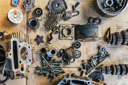 Old parts of motorcycles background. Repair and maintenance old parts of engine. Old motorcycle spare parts on corrugated paper background. Disassembly of spare parts, gear, differential, engine, old.の写真素材
