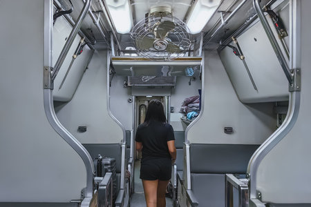 Young asian woman walking while looking for her passenger seat in train car aisle. Woman walk to...