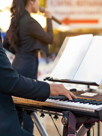 Pianist male hands playing electric piano with the band on stage. Classical concert, performance rehearsal, show. Learning to play a musical instrument. Hands of musician or artist play synthesisers.の写真素材
