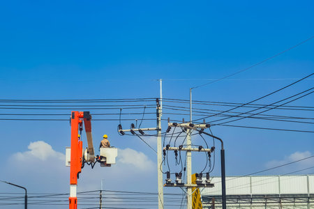 Electricians or engineer on bucket boom truck work to install electrical system on power pole with...
