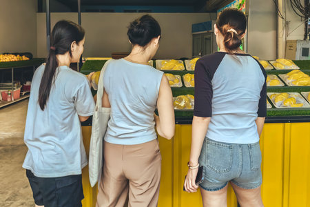 Young woman and friend choose to buy durian was cut and packed ready to eat. Asian women selecting...