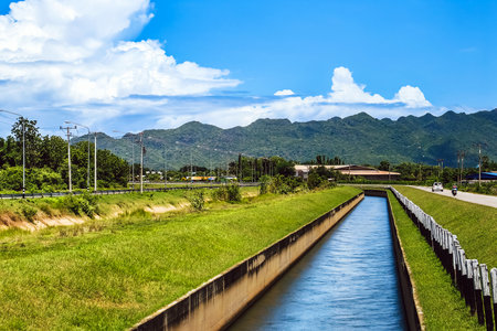 Irrigation canal or irrigation channel in concrete wall send water from the reservoir to agricultural area. Canal system for water supply system with beautiful rural scenery. Canal with flowing water.の写真素材