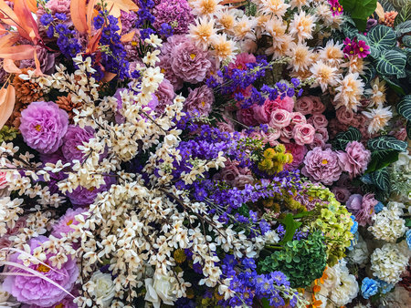 Decorated and embellished with beautiful vibrant artificial flower bouquets arrangements. Colorful artificial flowers as background or backdrop. Multicolored floral pattern wallpaper. Adorned flowersの写真素材