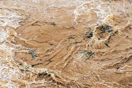 Smudged water flows profusely. River water flowing profusely. Flood waters rushing down river after storm flows through. Turbulent river dam. Water turbulence of river due to dam. Water Nature Textureの写真素材