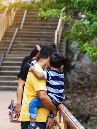 Back view of lovely father holding son enjoy walking on the walkway with beautiful nature scenic landscape with stone mountain range also call Snake Mountain at Khao Ngu Stone Park. Amazing nature.の写真素材
