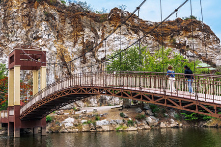 Back view of female friends take leisure stroll on suspension bridge with beautiful nature scenic landscape with stone mountain range also call Snake Mountain at Khao Ngu Stone Park. Amazing nature.の写真素材