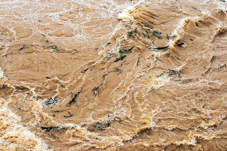 Smudged water flows profusely. River water flowing profusely. Flood waters rushing down river after...