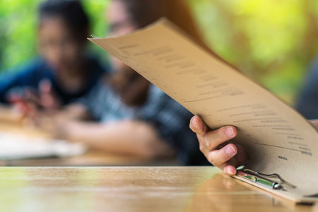 Close up to woman finger with menu choosing dishes at restaurant. A person reading menu at table....
