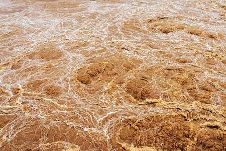 Smudged water flows profusely. River water flowing profusely. Flood waters rushing down river after...