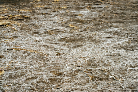 Smudged water flows profusely. River water flowing profusely. Flood waters rushing down river after storm flows through. Turbulent river dam. Water turbulence of river due to dam. Water Nature Textureの写真素材