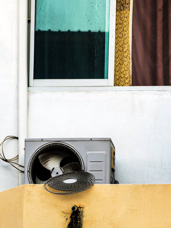 Compressor fan with broken cover. Old dirty broken condensing unit outside building. Damaged air compressor of air conditioner with dirty on wall outdoor. Broken air conditioner condenser unit outsideの写真素材