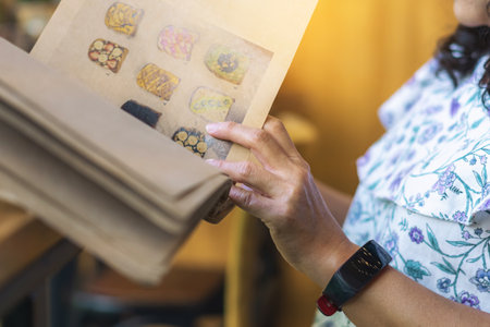 Close up to woman finger with menu choosing dishes at restaurant. A person reading menu at table. Woman with menu in restaurant making order. People select order from menu. Order food through menu.の写真素材