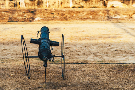 Replica of ancient cannon made of black painted steel on field can emits smoke and makes a sound...