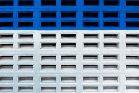 Colorful concrete ventilation block wall painted in vibrant blue and white. View of patterned concrete ventilation block painted blue and white, showing geometric shape and texture. Brick wall paintedの写真素材