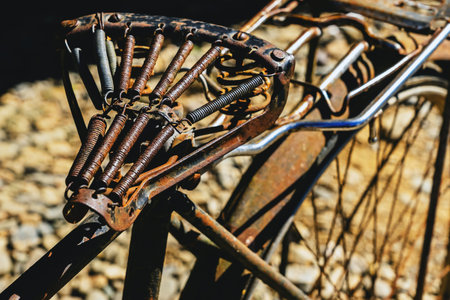 Close up of old vintage bicycle saddle frame, heavily aged with rust and showing intricate coil spring mechanism. The leather padding is completely gone, revealing the weathered iron structure.の写真素材