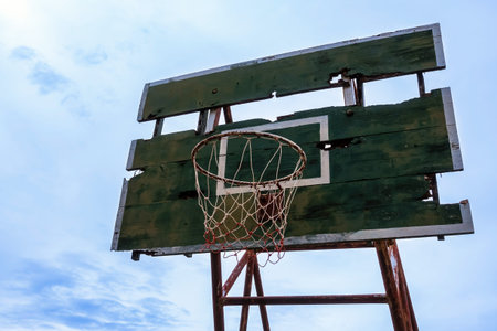 Low angle shot of aged and rustic weathered basketball rim and distressed backboard. Old abandoned...
