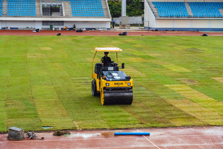 KANCHANABURI, THAILAND-AUGUST 8, 2025 : Unidentified team of landscape workers installing fresh natural sod rolls on prepared soil ground for professional sports field project at Kleeb Bua Stadium.のeditorial素材