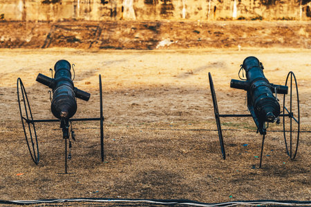 Replica of ancient cannon made of black painted steel on field can emits smoke and makes a sound like a real bullet being fired using an electronic system to accompany the outdoor retro performance.