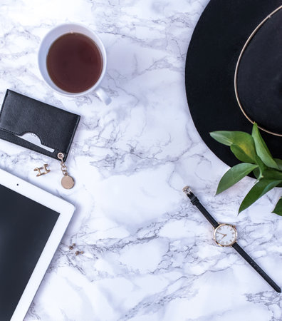 A white mug with black coffee on a white countertop. There are white meringues nearby. A phone, a...