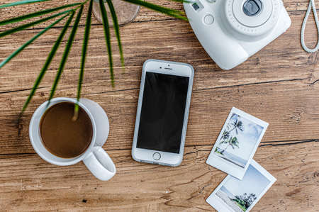 Coffee mug, camera, cell phone on a wooden surface. Top viewの写真素材