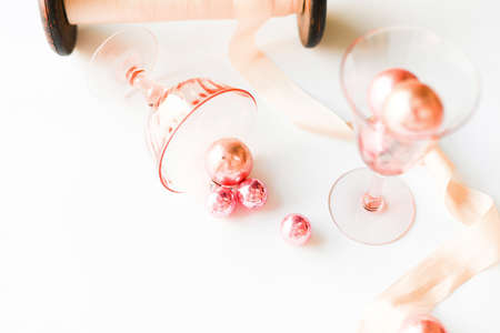 A pink spool of thread lies on a white background and pink objects around