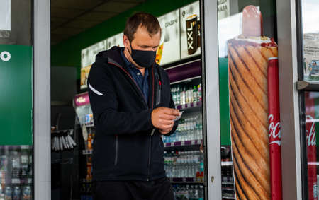 Lutsk, Ukraine - May 20,2020: a man in face mask checking the bill at the exit of grocery store...