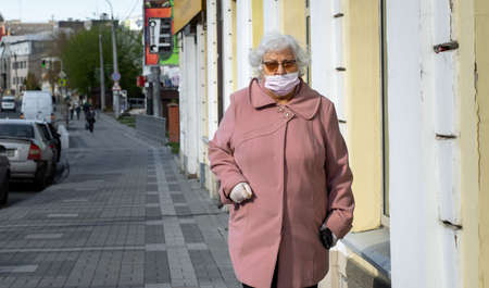 Lutsk, Ukraine - May 20,2020: Grandma wearing face mask on a public streets in the middle of coronavirus epidemic. Health protection, virus outbreak prevention during infectious diseases in the cityのeditorial素材