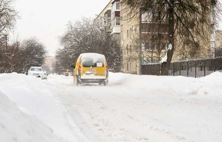 Lutsk, Ukraine - February 12,2020: City street after blizzard. Stuck car in snow and ice. Buried vehicle in snowdrift. Parking in winter after snowfall. Uncleaned road. Record-breaking amounts of snowのeditorial素材