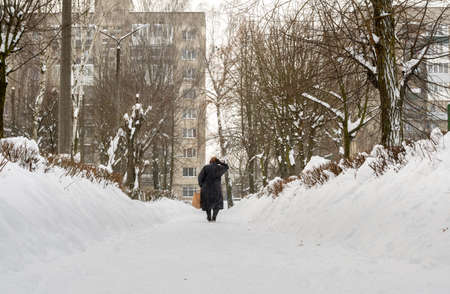 Lutsk, Ukraine - February 12,2020: People on street after snow storm. City street after blizzard. Record-breaking amounts of snow. Uncleaned slippery roads and sidewalk in winter. Cars in snowdriftのeditorial素材