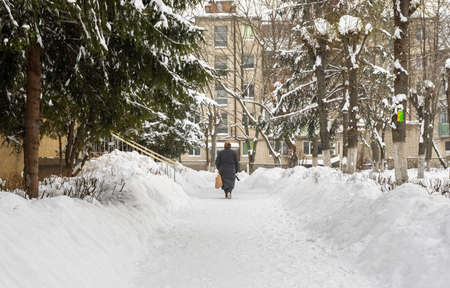 Lutsk, Ukraine - February 12,2020: People on street after snow storm. City street after blizzard. Record-breaking amounts of snow. Uncleaned slippery roads and sidewalk in winter. Cars in snowdriftのeditorial素材