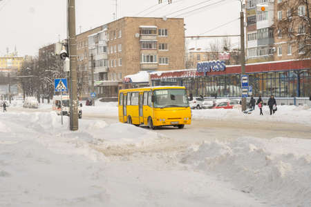 Lutsk, Ukraine - February 12,2020: Uncleaned slippery roads and sidewalk in winter. Cars in snowdrift. People on street after snow storm. City street after blizzard. Record-breaking amounts of snowのeditorial素材